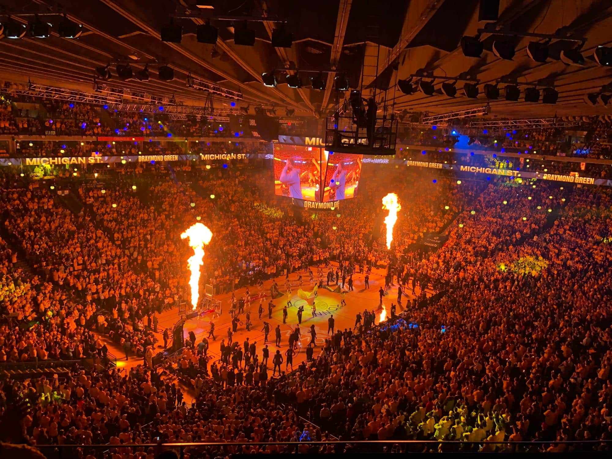 Packed basketball arena with fans under bright lights